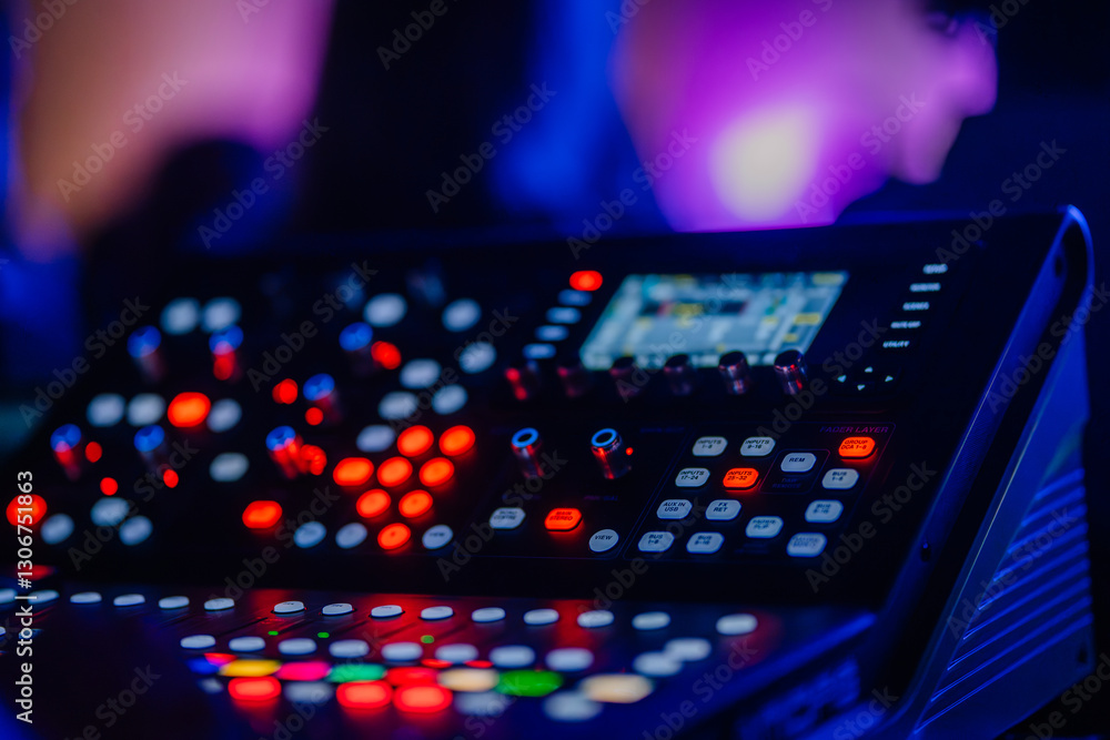 Fototapeta premium A close-up of a professional audio mixing console with illuminated buttons and knobs in a dimly lit environment, creating a vibrant atmosphere.
