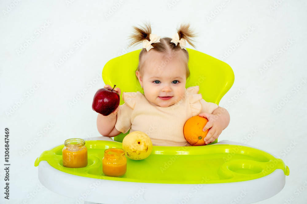 baby eats fruit puree in a high chair, baby food concept, little baby girl eats fruit on a white isolated background, place for text baby eats fruit puree in a high chair, baby food concept, little baby girl eats fruit on a white isolated background, place for text