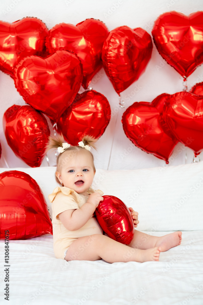 a baby girl among hearts, a small child on a bed with balloons in the form of hearts, the concept of valentine's day a baby girl among hearts, a small child on a bed with balloons in the form of hearts, the concept of valentine's day