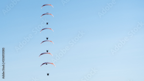 Formacja motoparalotniarzy w locie na tle błękitnego nieba
