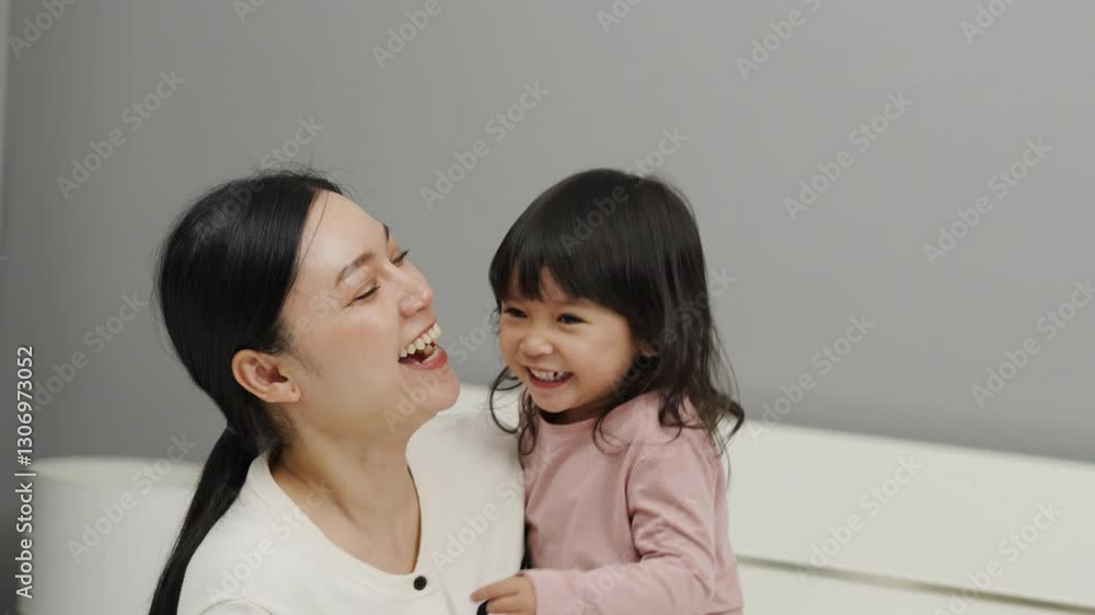 cheerful mother and toddler baby girl playing on a bed cheerful mother and toddler baby girl playing on a bed