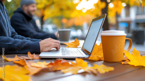 serene outdoor setting with digital marketer working on laptop surrounded by autumn leaves and warm beverages. vibrant fall colors create cozy atmosphere