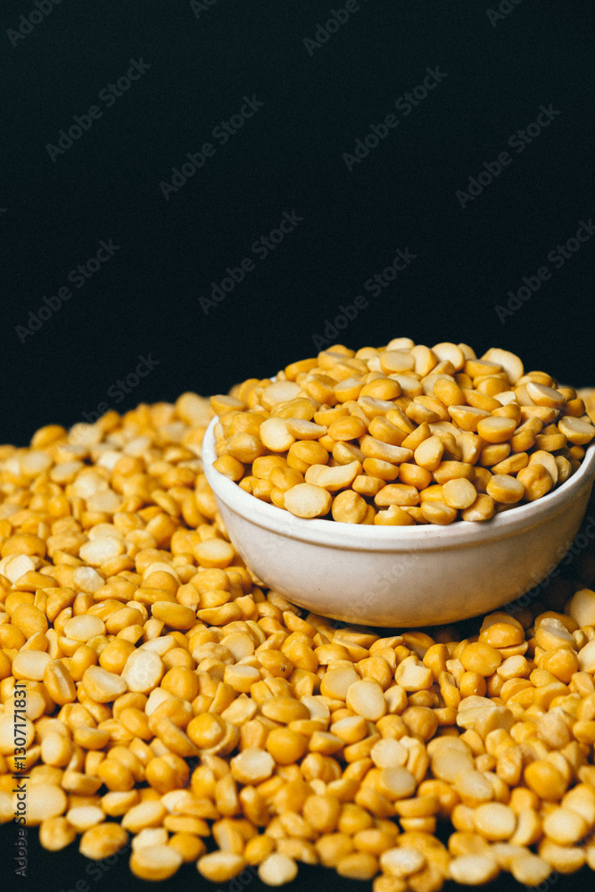 Portrait of Organic Bengal Gram (Cicer arietinum) placed in a ceramic white bowl, with split yellow chana dal forming the gradient background. Portrait of Organic Bengal Gram (Cicer arietinum) placed in a ceramic white bowl, with split yellow chana dal forming the gradient background.