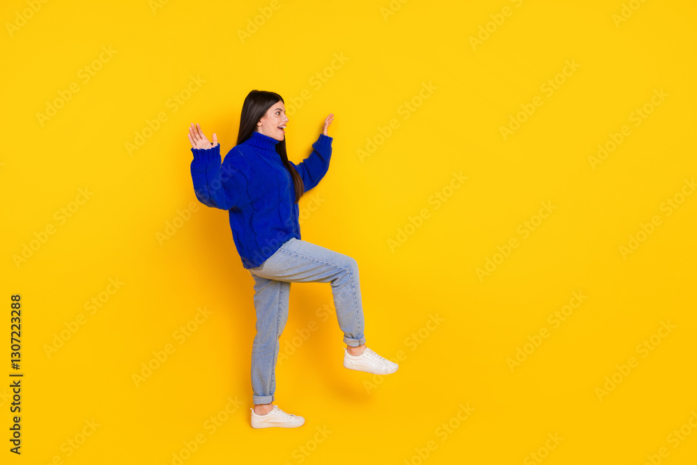 Cheerful young woman in a blue sweater gesturing playfully against a vibrant yellow background Cheerful young woman in a blue sweater gesturing playfully against a vibrant yellow background