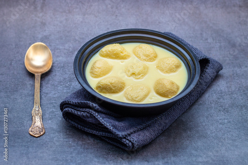 Rasmalai is a soft, spongy Indian dessert made of chhena (paneer) dumplings soaked in sweet, flavored milk, garnished with saffron, cardamom, and nuts. photo