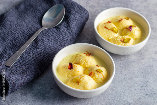 Rasmalai is a soft, spongy Indian dessert made of chhena (paneer) dumplings soaked in sweet, flavored milk, garnished with saffron, cardamom, and nuts. photo