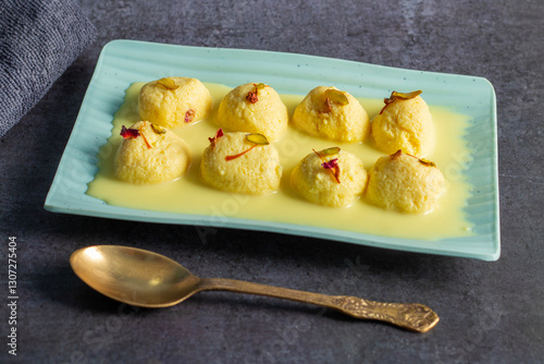 Rasmalai is a soft, spongy Indian dessert made of chhena (paneer) dumplings soaked in sweet, flavored milk, garnished with saffron, cardamom, and nuts. photo