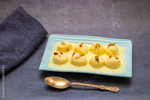 Rasmalai is a soft, spongy Indian dessert made of chhena (paneer) dumplings soaked in sweet, flavored milk, garnished with saffron, cardamom, and nuts. photo