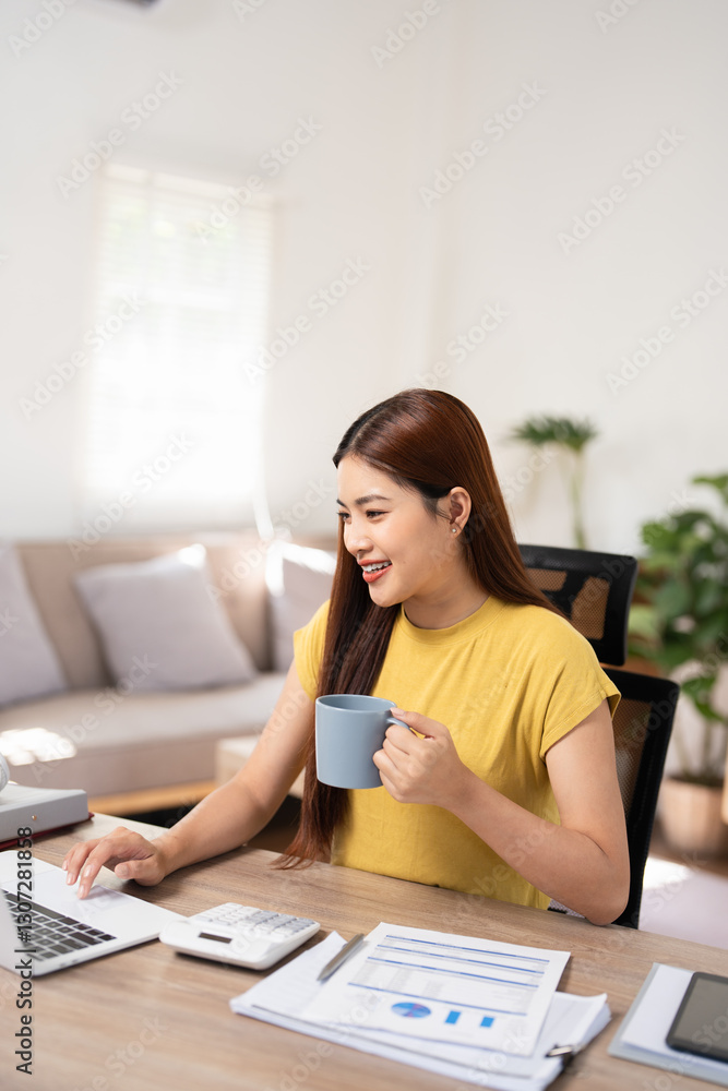 Beautiful happy smiling young Entrepreneur woman sitting at home office desk with cup of coffee, working on laptop in cozy interior. Attractive cheerful model using computer, typing. Indoors Beautiful happy smiling young Entrepreneur woman sitting at home office desk with cup of coffee, working on laptop in cozy interior. Attractive cheerful model using computer, typing. Indoors