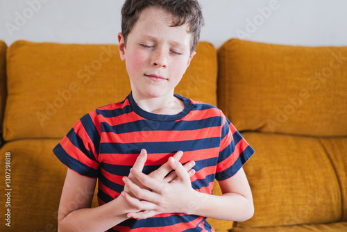 Young boy experiencing discomfort while sitting on a cozy couch at home