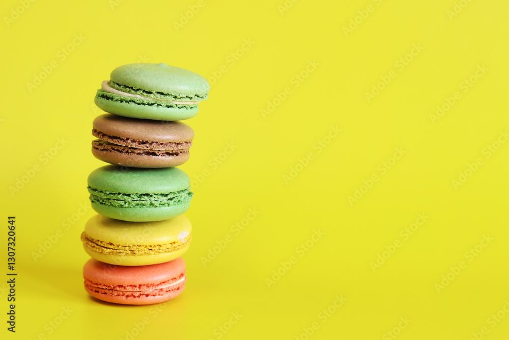 Stack of colorful macarons close-up. Bright French macarons on yellow background, side view. Assortment of macarons with different flavors. Delicious pastries, cookies, food background. Sweets tower Stack of colorful macarons close-up. Bright French macarons on yellow background, side view. Assortment of macarons with different flavors. Delicious pastries, cookies, food background. Sweets tower