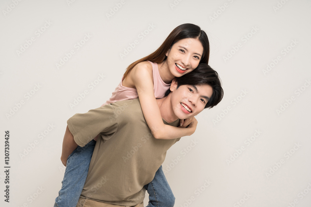 Fototapeta premium Piggyback ride Happy asian couple attractive in various action gesture standing on isolated white background. Cheerful Smiling young man and woman fun with piggyback ride