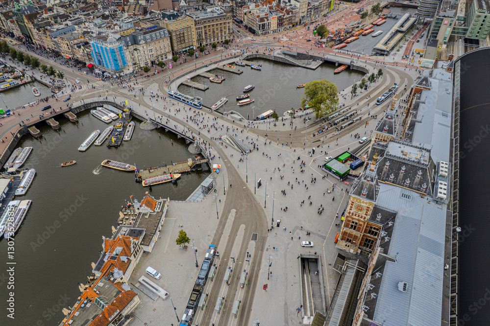 Fototapeta premium Beautiful aerial view of Amsterdam Centraal Train Station and its historic hub with canals, bikes, cafes. Netherlands