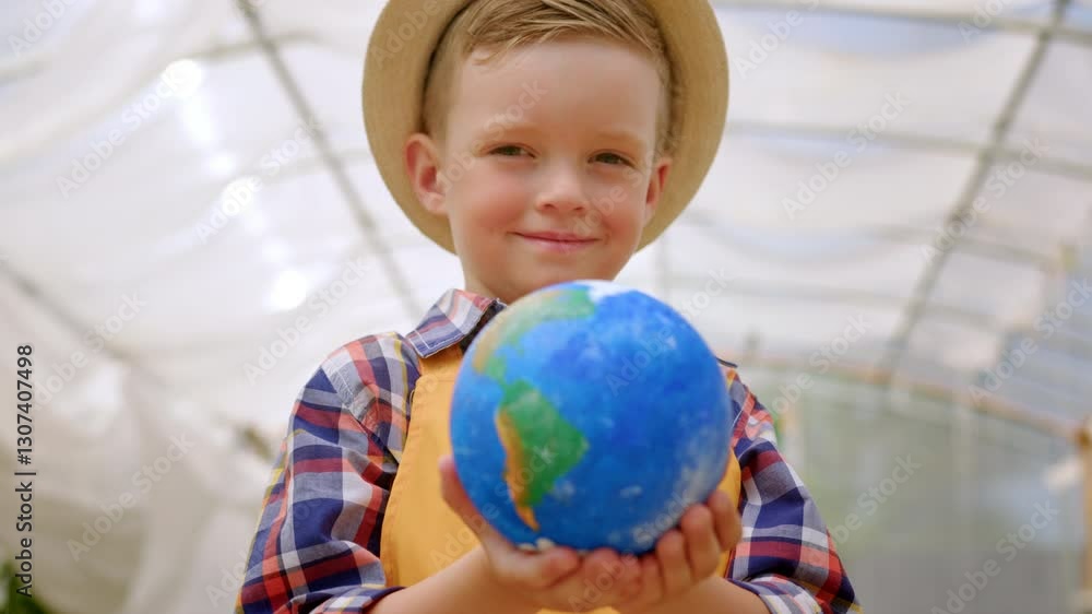 Preschooler boy in hat holds Earth model calling for ecosystem conservation Preschooler boy in hat holds Earth model calling for ecosystem conservation
