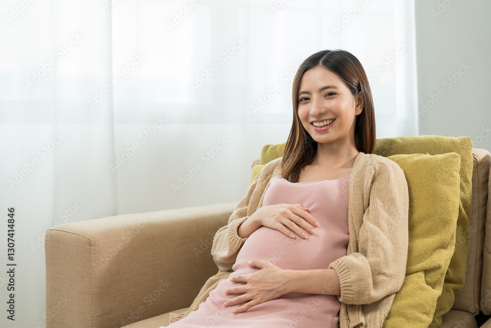 Happy pregnant woman caresses her belly while taking rest on sofa at home, concept of happy motherhood waiting for childbirth, family planning and pregnancy with insurance for child health. Happy pregnant woman caresses her belly while taking rest on sofa at home, concept of happy motherhood waiting for childbirth, family planning and pregnancy with insurance for child health.