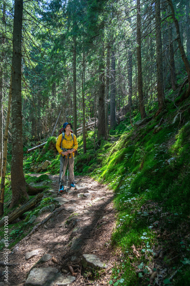 Young mountaineer trekking through a lush forest trail on a sunny day, looking away and contemplating the journey. Young mountaineer trekking through a lush forest trail on a sunny day, looking away and contemplating the journey.