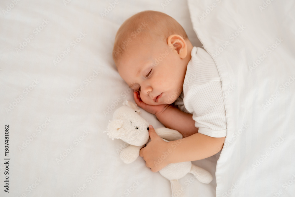 a newborn baby sleeps sweetly holding a toy in his hands, a place for text, a baby sleeps on a white bed under a blanket with a pen under his cheek, a healthy baby's sleep a newborn baby sleeps sweetly holding a toy in his hands, a place for text, a baby sleeps on a white bed under a blanket with a pen under his cheek, a healthy baby's sleep