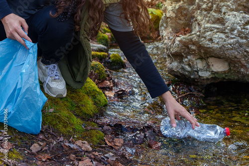 фотографія Volunteer collecting plastic bottle from polluted stream during environmental cl
