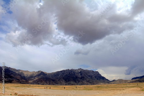 Expansive Desert Landscape with Dramatic Clouds and Distant Mountain Peaks, Cabul, Afganistan photo