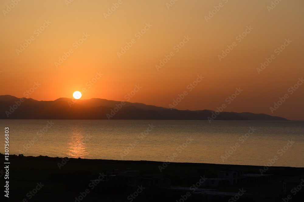 Breathtaking sunset casts golden hues over tranquil waters and distant hills Breathtaking sunset casts golden hues over tranquil waters and distant hills