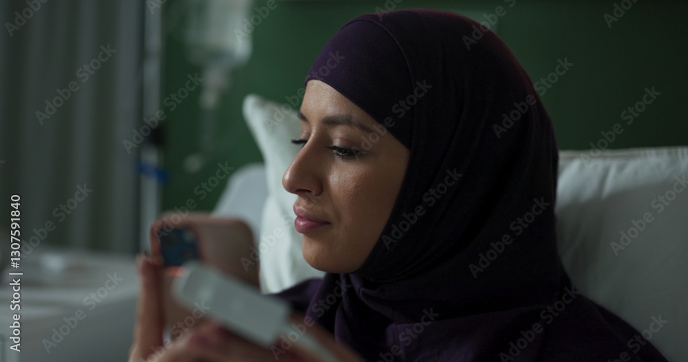 Young Arab patient, sitting in bed, texting on her phone. Young Arab patient, sitting in bed, texting on her phone.