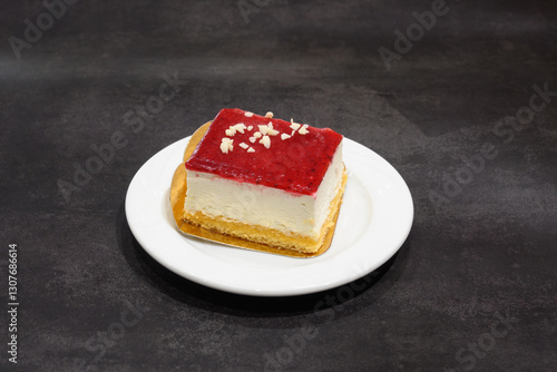 A slice of cake with a cherry on top sits on a white plate