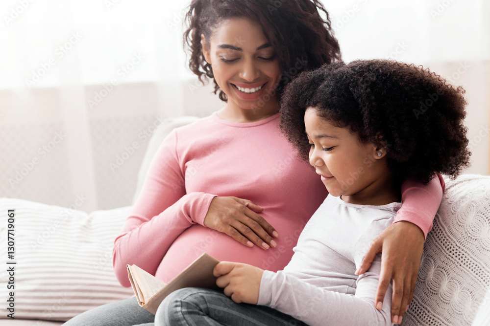 Adorable Little Girl Reading Book With Her Pregnant Mom While Spending Time In Living Room Together Adorable Little Girl Reading Book With Her Pregnant Mom While Spending Time In Living Room Together