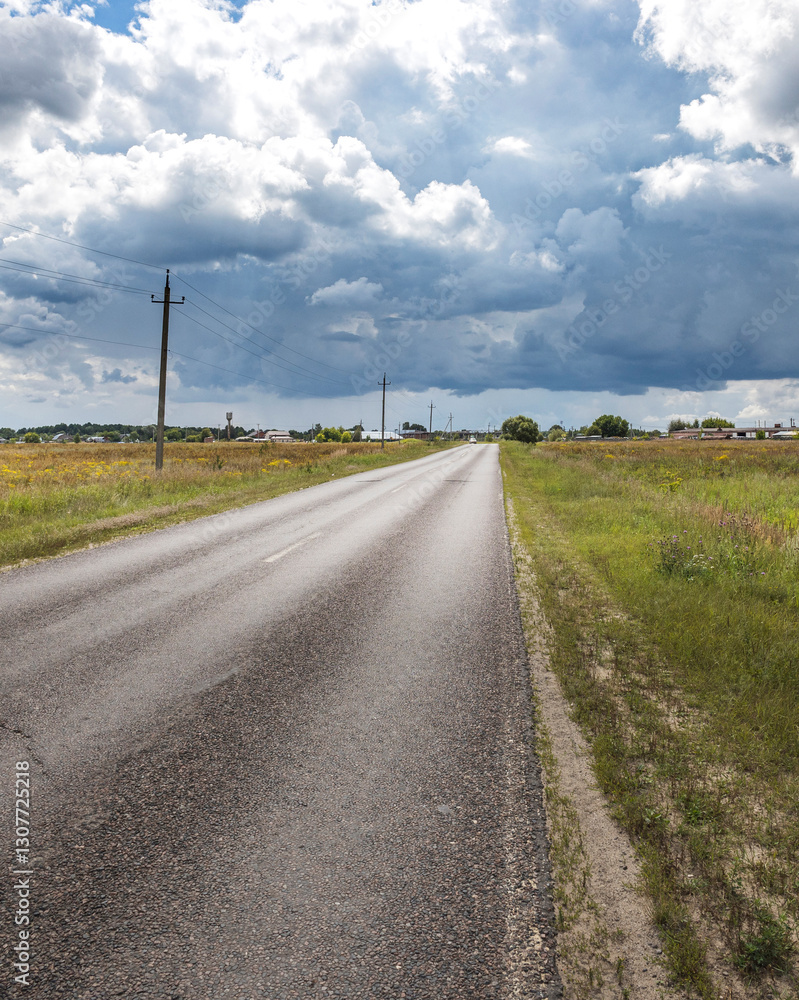 Road with a few trees in the background and a cloudy sky Road with a few trees in the background and a cloudy sky