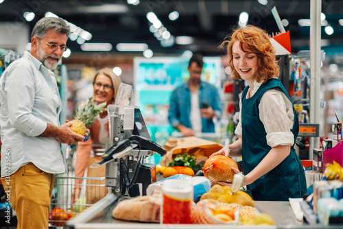 Cashier scanning groceries at checkout counter in supermarket