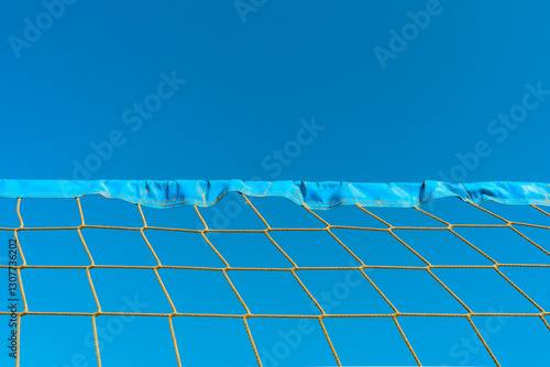 Close up shot of volleyball net, blue sky, view from below