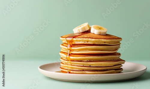 Wallpaper Mural Delicious caramelized banana pancakes topped with maple syrup on a cream plate with a mint green background Torontodigital.ca