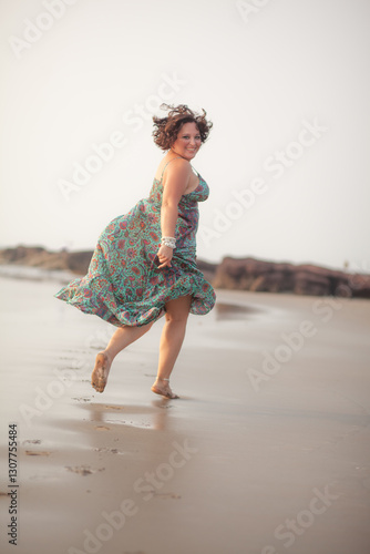 A beautiful fat girl in a summer Indian sundress walks along the sandy shore of the ocean
