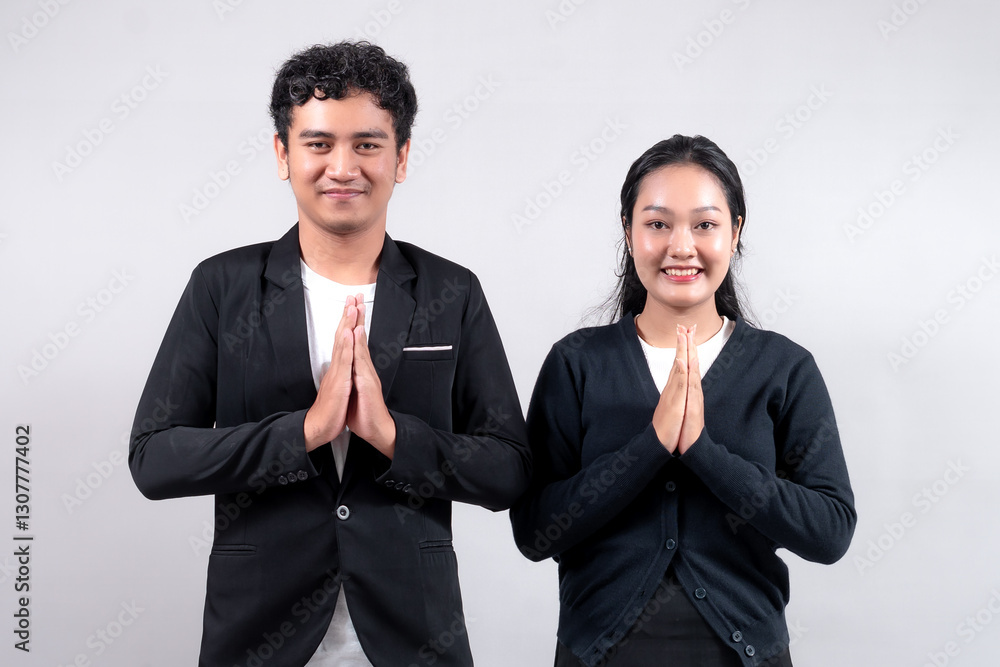 Asian man and woman standing together, smiling, and greeting with a traditional Namaste gesture. They wear business attire, symbolizing respect, culture, hospitality, and professionalism. Asian man and woman standing together, smiling, and greeting with a traditional Namaste gesture. They wear business attire, symbolizing respect, culture, hospitality, and professionalism.