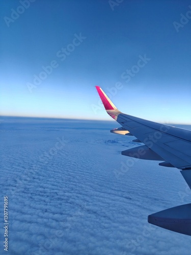 An airplane wing in flight above the clouds, seen from inside the aircraft