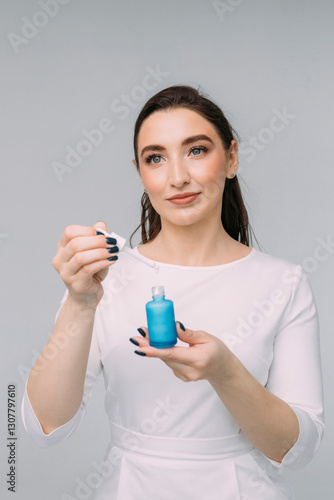 girl cosmetologist with long hair in a white dress holds a blue jar with facial serum in her hands