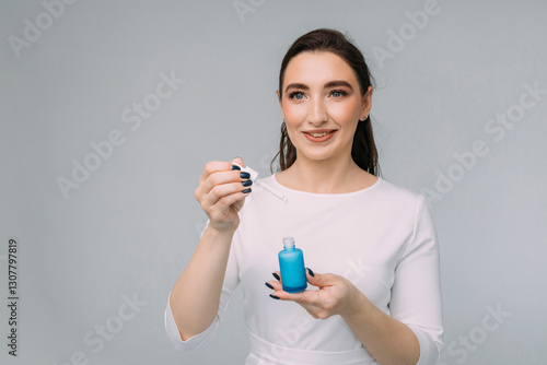 girl cosmetologist with long hair in a white dress holds a blue jar with facial serum in her hands