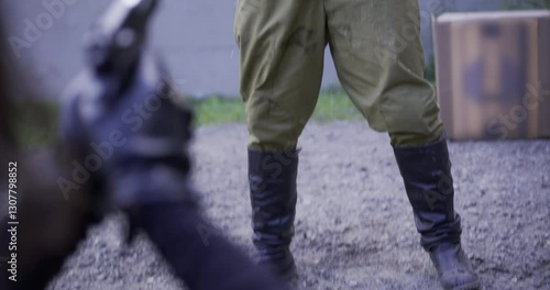 Funny shot of guard peeing his pants in over the top fashion as guy points gun at him