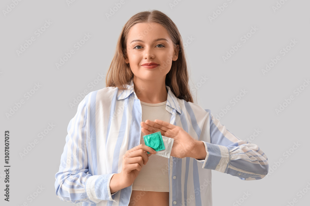 Young woman with condom on light background Young woman with condom on light background