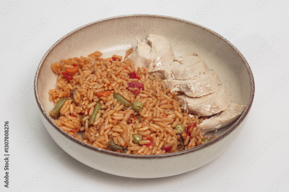 The image shows a delicious-looking meal consisting of a bed of seasoned rice with vegetables, accompanied by slices of cooked chicken. The image shows a delicious-looking meal consisting of a bed of seasoned rice with vegetables, accompanied by slices of cooked chicken.
