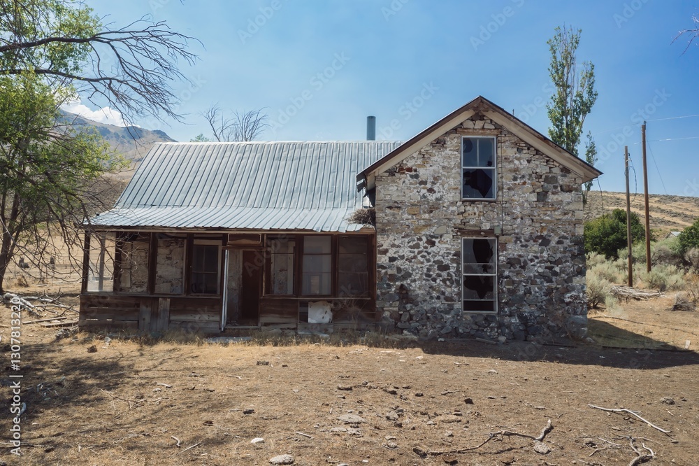 An abandoned stone farmhouse with broken windows stands in a dry field in Oregon, USA. The building's weathered facade tells a story of forgotten times. ,Fields, USA An abandoned stone farmhouse with broken windows stands in a dry field in Oregon, USA. The building's weathered facade tells a story of forgotten times. ,Fields, USA