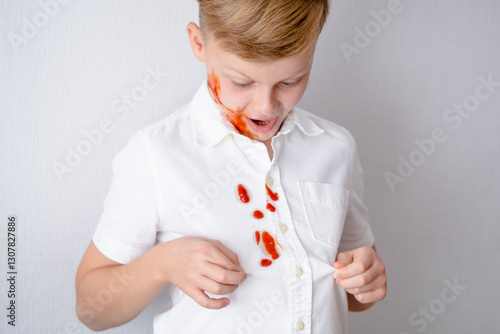 Spilled tomato sauce or ketchup on the clothing. Faceless child playful covered in ketchup enjoys a messy lunch while showing his stained white shirt against. everyday life stain concept.