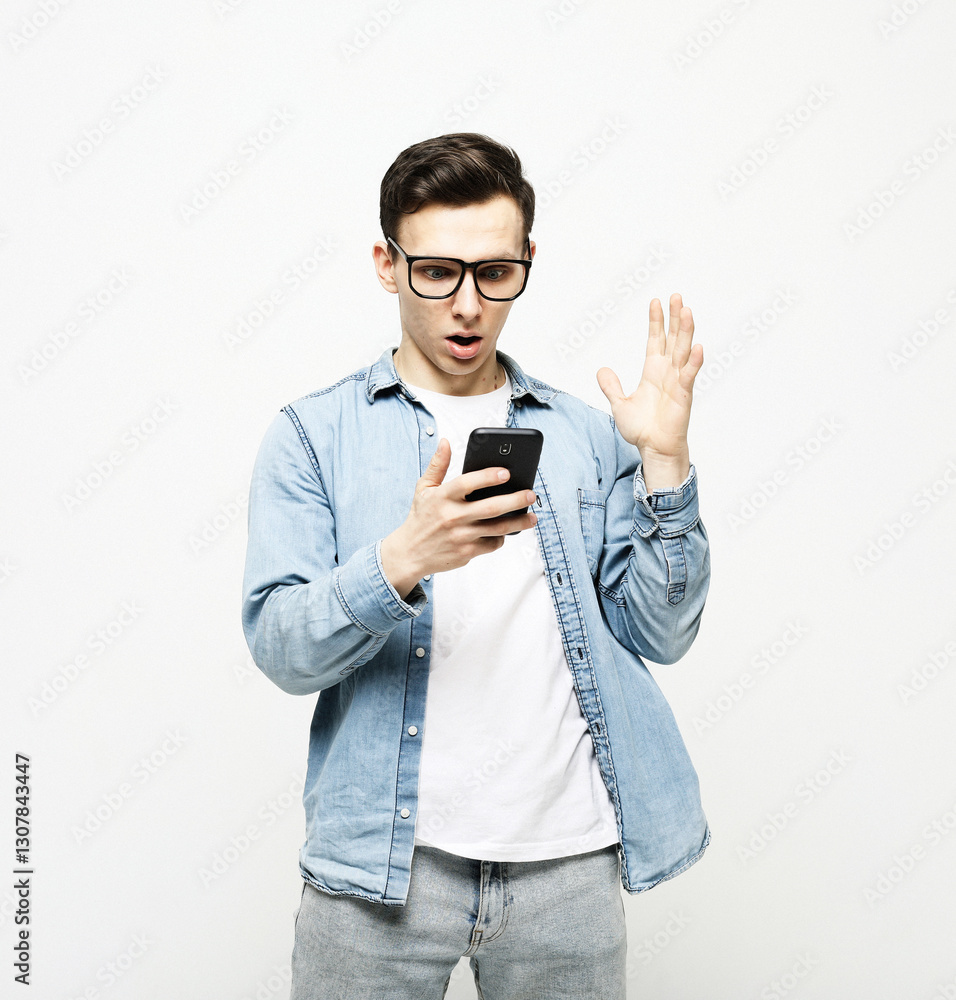 A shocked and dumbfounded man looks at his smartphone reading bad news A shocked and dumbfounded man looks at his smartphone reading bad news