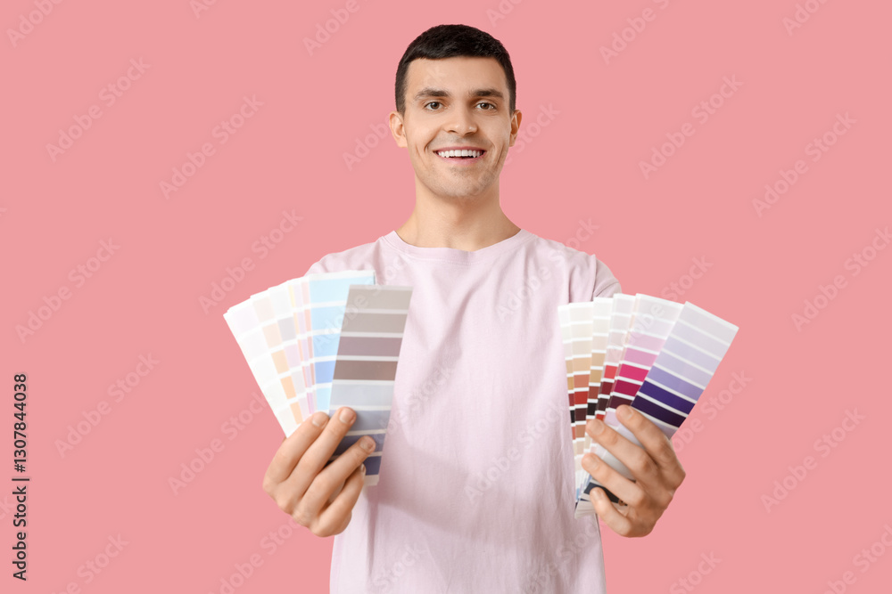 Young man with paint palettes on pink background Young man with paint palettes on pink background