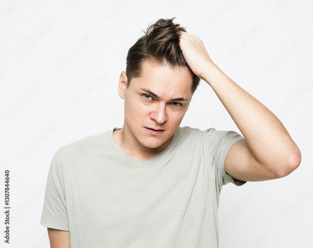 a young handsome man touches his head thoughtfully, thinking about something