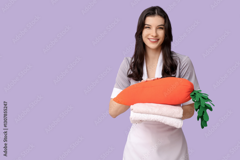 Happy female chambermaid with toy carrot and stack of towels on purple background. Easter celebration Happy female chambermaid with toy carrot and stack of towels on purple background. Easter celebration