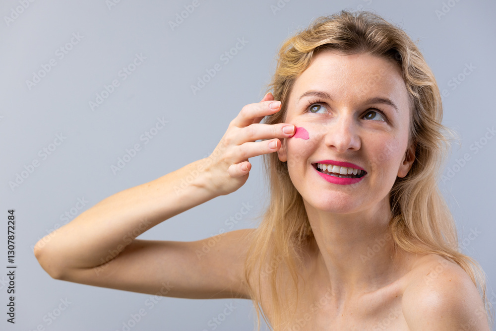 Woman Applying Skincare on Her Cheek and Smiling, Emphasizing the Importance of Self-Care and Beauty Routines in Modern Lives Woman Applying Skincare on Her Cheek and Smiling, Emphasizing the Importance of Self-Care and Beauty Routines in Modern Lives
