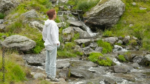 Wallpaper Mural Enjoy the mountain streams. Young hiker is standing near a creek flowing through a rocky landscape. She is looking at the water running between the stones Torontodigital.ca