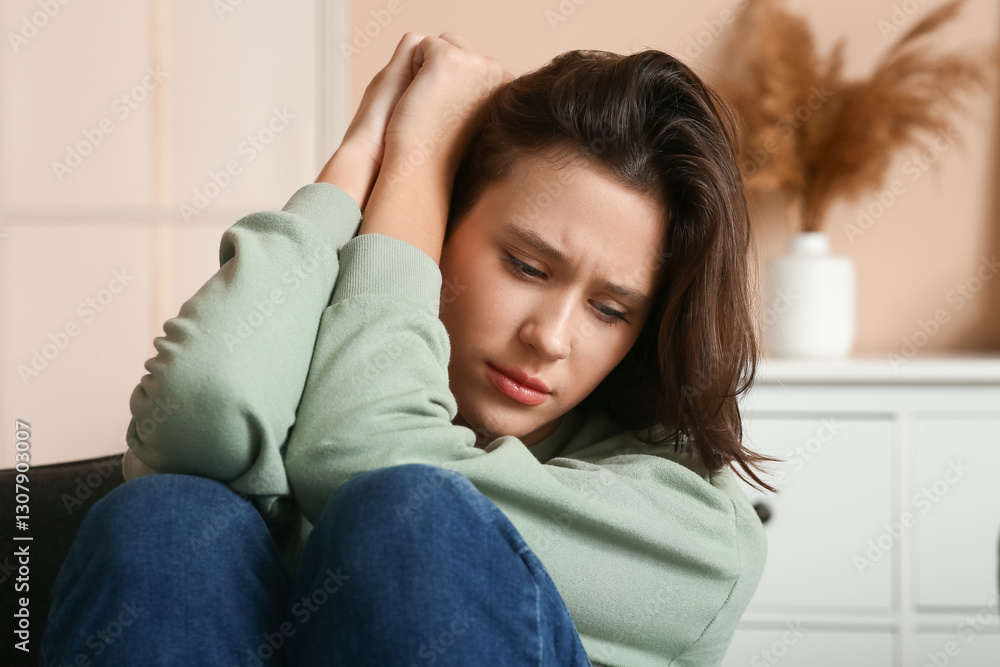 Depressed young woman sitting in armchair in living room. Closeup Depressed young woman sitting in armchair in living room. Closeup