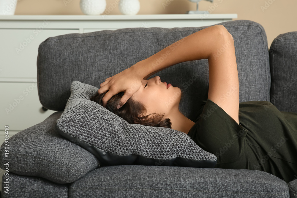 Obraz premium Depressed young woman lying on sofa in living room
