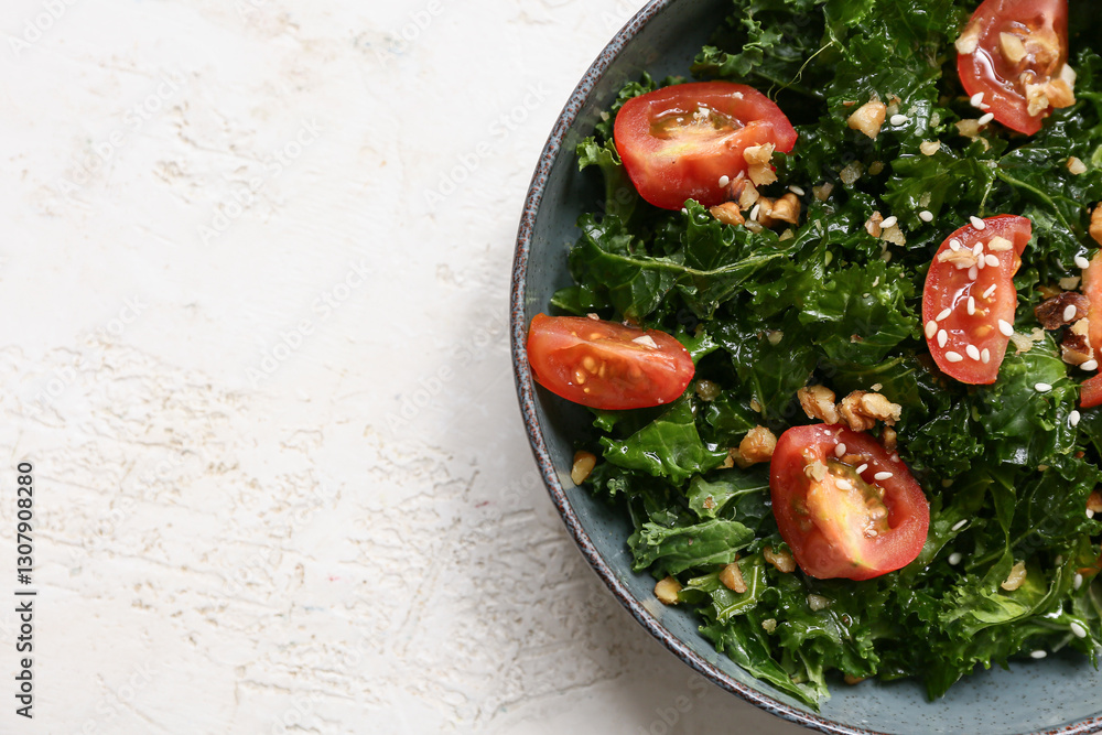 Fototapeta premium Bowl of tasty kale salad with tomatoes and walnuts on light background